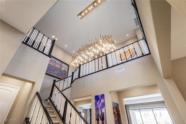 staircase with a towering ceiling and a chandelier