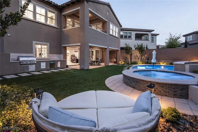 exterior space featuring a yard, a balcony, a patio area, an in ground hot tub, and area for grilling