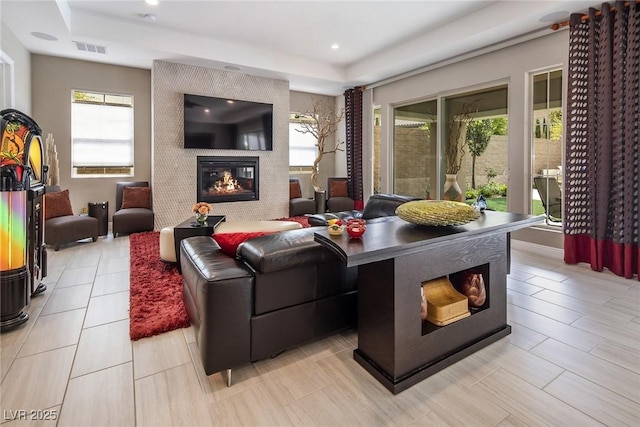 living room with plenty of natural light, a raised ceiling, and a fireplace