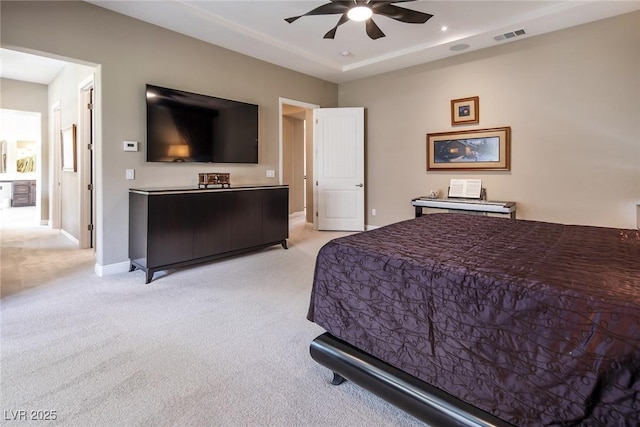 carpeted bedroom with ceiling fan and a tray ceiling