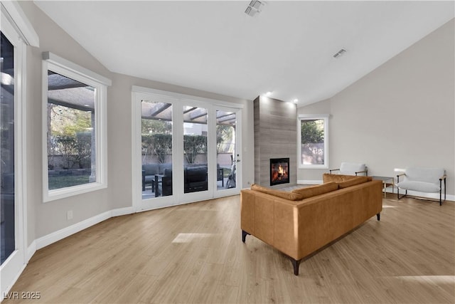 living room featuring light hardwood / wood-style flooring, a healthy amount of sunlight, and vaulted ceiling