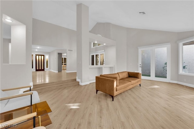 living room with high vaulted ceiling and light hardwood / wood-style flooring