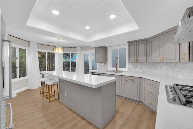 kitchen with decorative backsplash, a center island, decorative light fixtures, and a raised ceiling