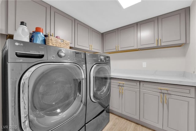 washroom with washer and clothes dryer, cabinets, and light hardwood / wood-style flooring