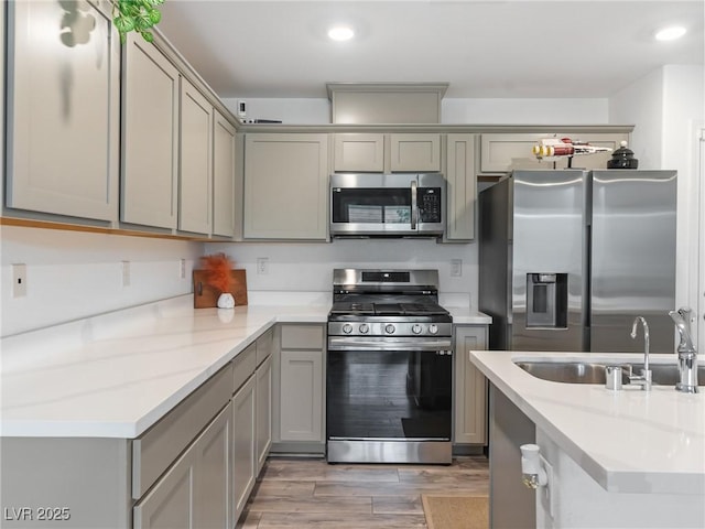 kitchen featuring gray cabinets, sink, light wood-type flooring, and appliances with stainless steel finishes