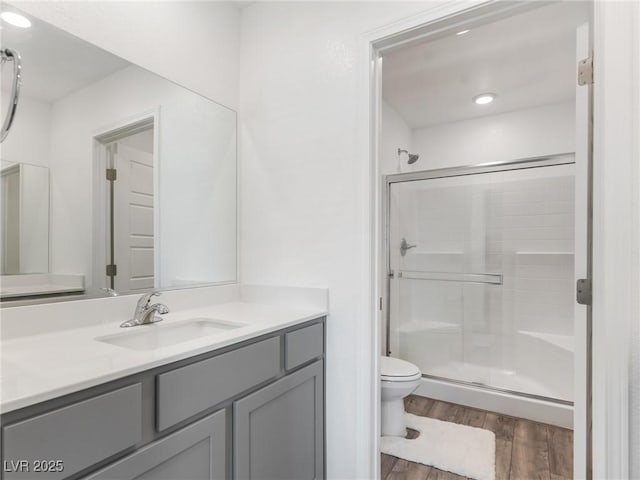 bathroom with toilet, an enclosed shower, wood-type flooring, and vanity