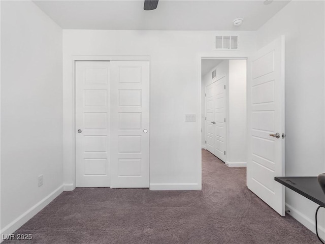 unfurnished bedroom featuring ceiling fan, a closet, and dark colored carpet