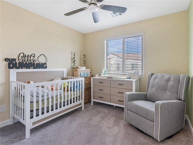 bedroom featuring carpet, ceiling fan, and a crib