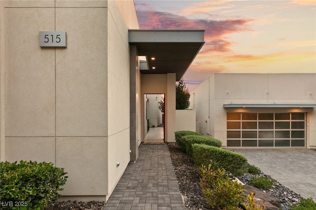 exterior entry at dusk featuring a garage