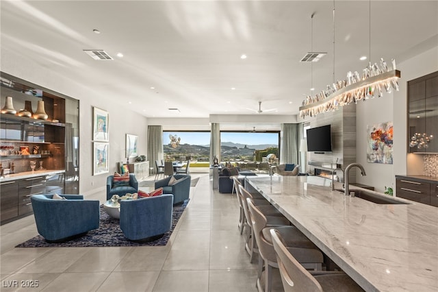 kitchen featuring pendant lighting, sink, ceiling fan, light stone counters, and a breakfast bar area