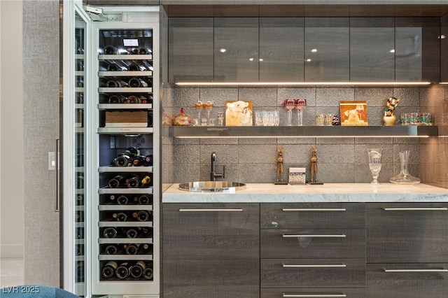 bar featuring light stone counters and sink