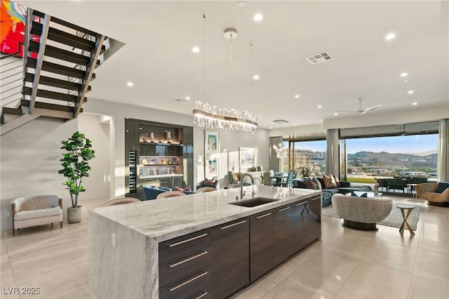 kitchen with a mountain view, hanging light fixtures, a kitchen island with sink, and sink