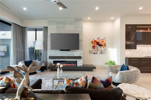 living room with a tile fireplace and ceiling fan