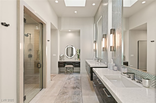 bathroom with decorative backsplash, a skylight, tile patterned floors, vanity, and a shower with door