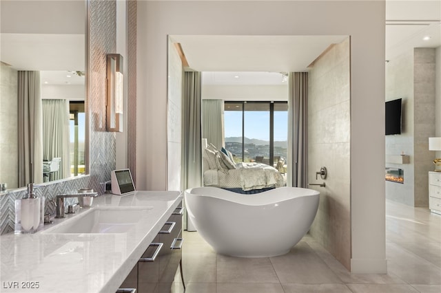 bathroom with ceiling fan, a large fireplace, a washtub, tile patterned floors, and vanity