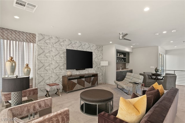 living room featuring bar area, ceiling fan, built in features, and light colored carpet