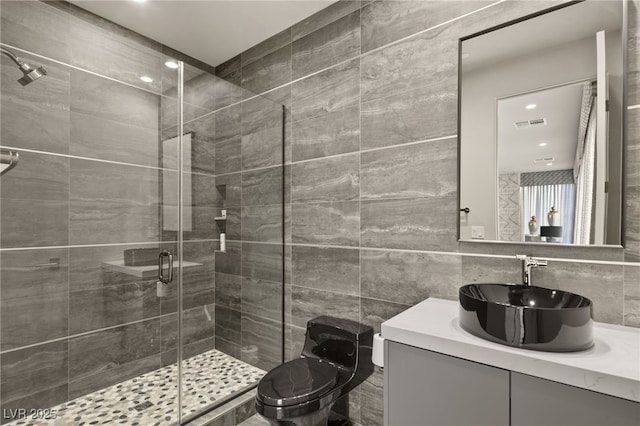 bathroom featuring tile walls, vanity, an enclosed shower, and toilet