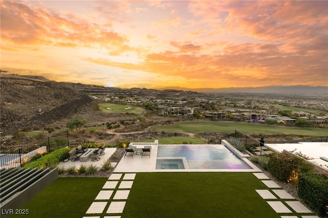 pool at dusk featuring a patio area, an in ground hot tub, and a yard