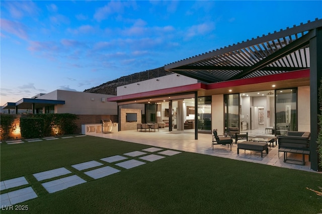 back house at dusk featuring area for grilling, a patio area, and a lawn