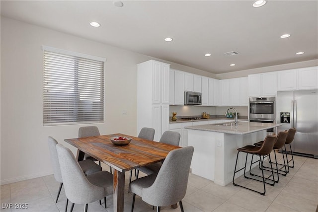 kitchen featuring white cabinets, a center island with sink, sink, and appliances with stainless steel finishes