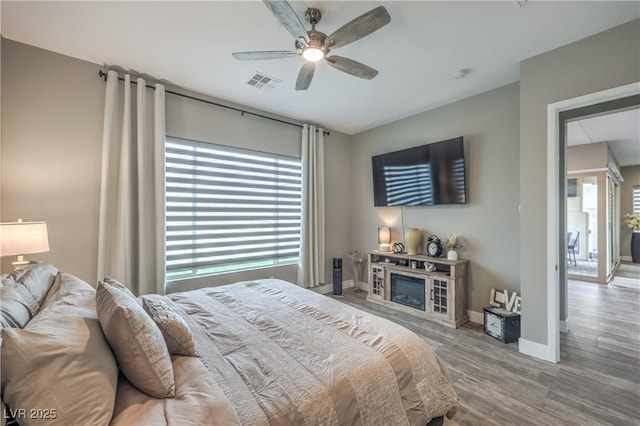 bedroom featuring multiple windows, ceiling fan, and wood-type flooring