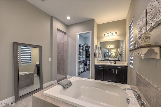 bathroom with tile patterned floors, vanity, and a relaxing tiled tub