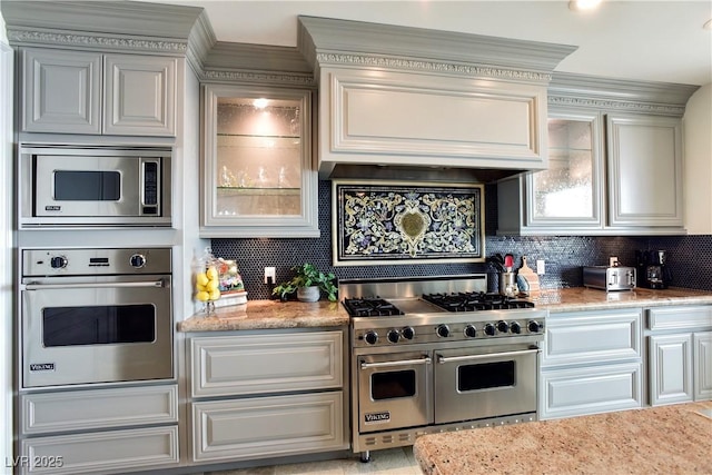 kitchen featuring stainless steel appliances, light stone counters, and tasteful backsplash