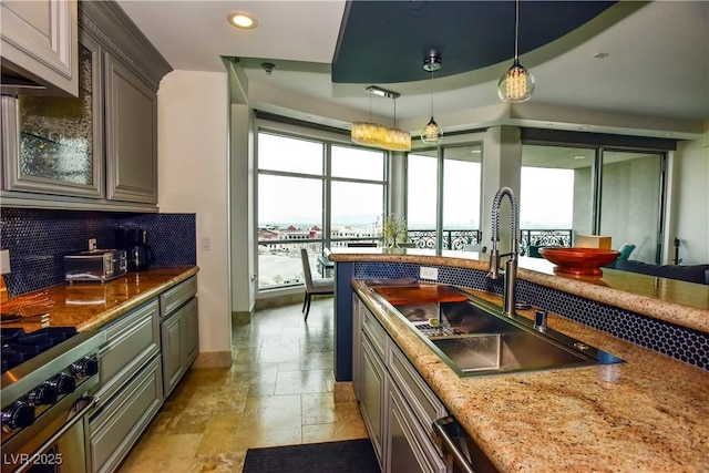 kitchen featuring decorative backsplash, decorative light fixtures, a raised ceiling, and sink