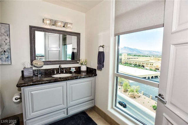 bathroom with a mountain view, vanity, tile patterned floors, and a wealth of natural light