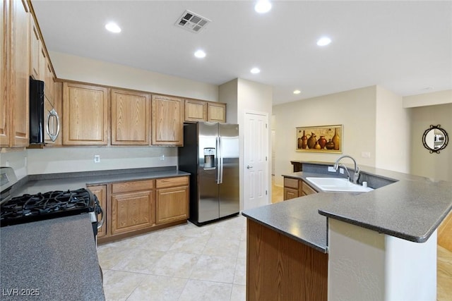 kitchen featuring visible vents, dark countertops, an island with sink, appliances with stainless steel finishes, and a sink