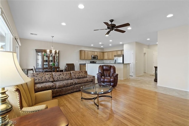 living area with visible vents, baseboards, light wood-type flooring, recessed lighting, and ceiling fan with notable chandelier