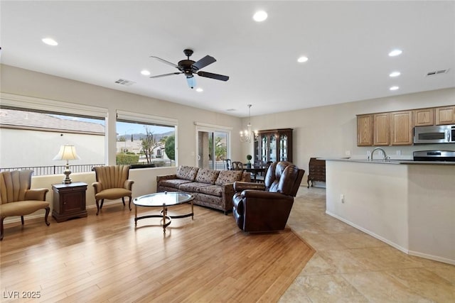 living area with recessed lighting, visible vents, light wood finished floors, and ceiling fan with notable chandelier