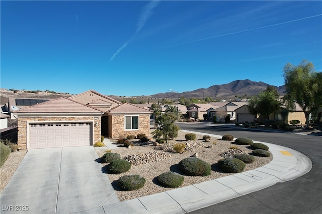 single story home featuring an attached garage, a tiled roof, concrete driveway, stone siding, and a mountain view