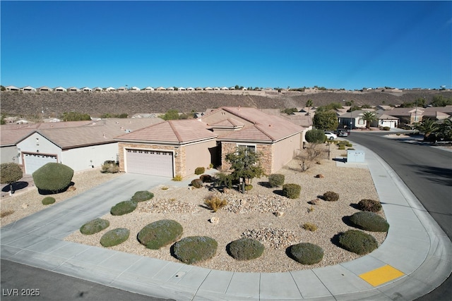 view of front facade with a garage, a residential view, stone siding, and driveway