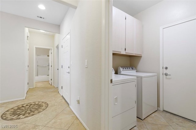 laundry room featuring cabinet space, light tile patterned floors, separate washer and dryer, and baseboards