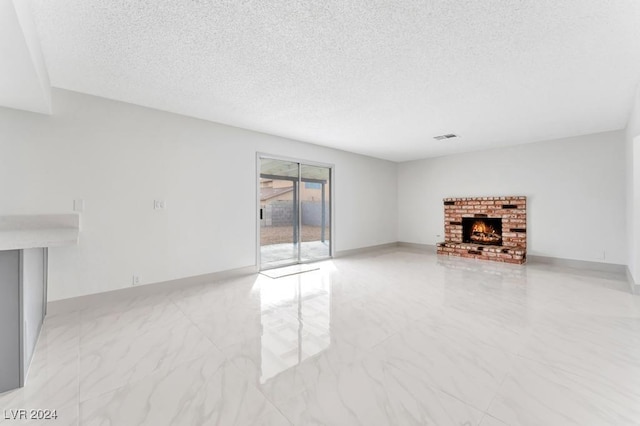 unfurnished living room featuring a textured ceiling and a brick fireplace