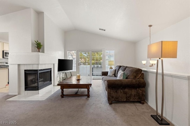 living room with a tiled fireplace, lofted ceiling, and light carpet