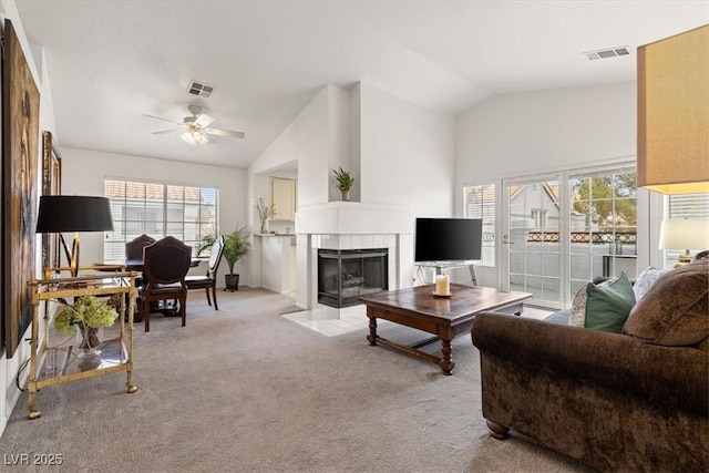 living room with vaulted ceiling, light colored carpet, ceiling fan, and a fireplace