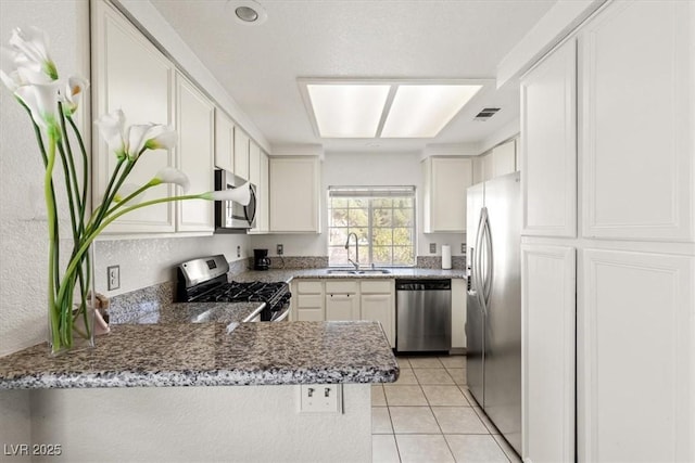 kitchen with white cabinetry, sink, light tile patterned floors, kitchen peninsula, and stainless steel appliances