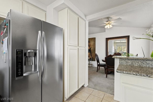 kitchen with dark stone countertops, stainless steel fridge with ice dispenser, white cabinetry, and lofted ceiling