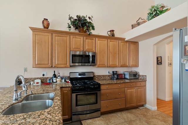 kitchen featuring light stone counters, sink, and appliances with stainless steel finishes