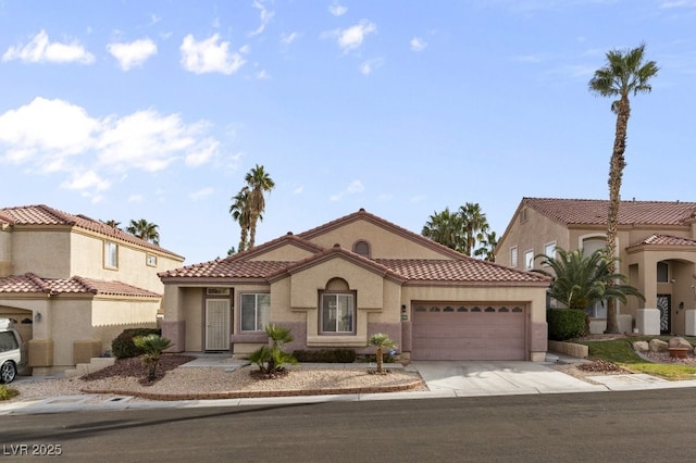 mediterranean / spanish home featuring a garage, concrete driveway, a tiled roof, and stucco siding