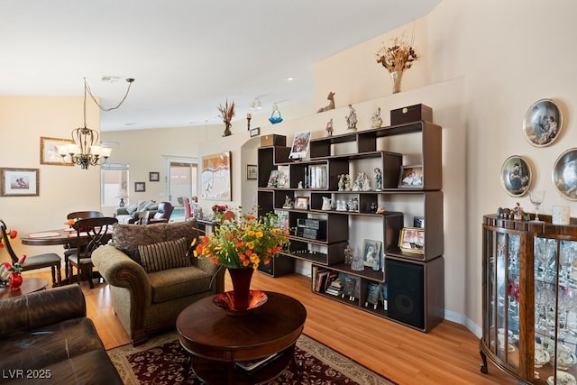 living area featuring a chandelier, vaulted ceiling, wood finished floors, and visible vents