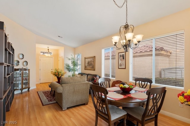 dining room featuring an inviting chandelier, light hardwood / wood-style floors, and vaulted ceiling