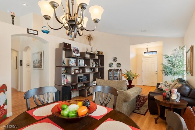 dining room featuring light hardwood / wood-style flooring, a chandelier, and lofted ceiling