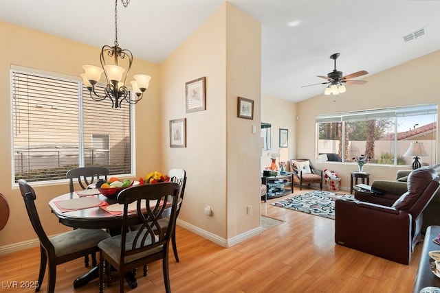 dining space with ceiling fan with notable chandelier, a healthy amount of sunlight, light wood-type flooring, and lofted ceiling