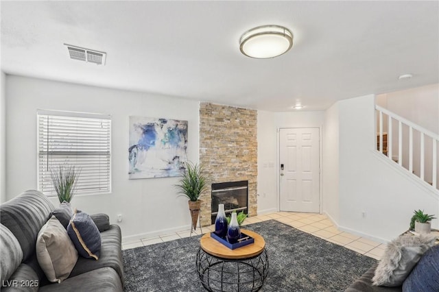 living room featuring a stone fireplace and light tile patterned flooring