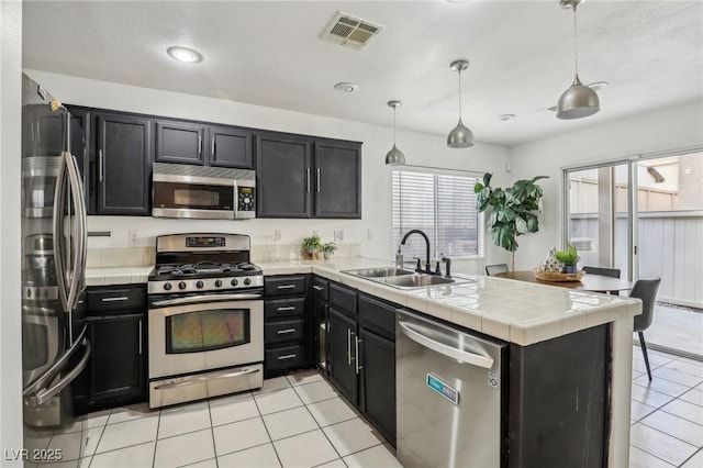 kitchen featuring kitchen peninsula, sink, pendant lighting, and appliances with stainless steel finishes