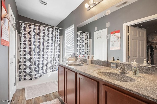 bathroom with lofted ceiling, wood-type flooring, vanity, and shower / tub combo with curtain