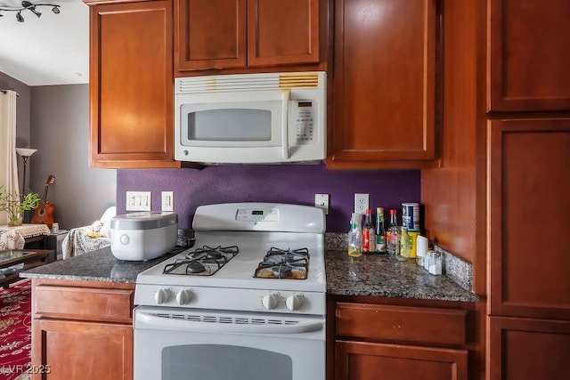 kitchen with dark stone countertops and white appliances